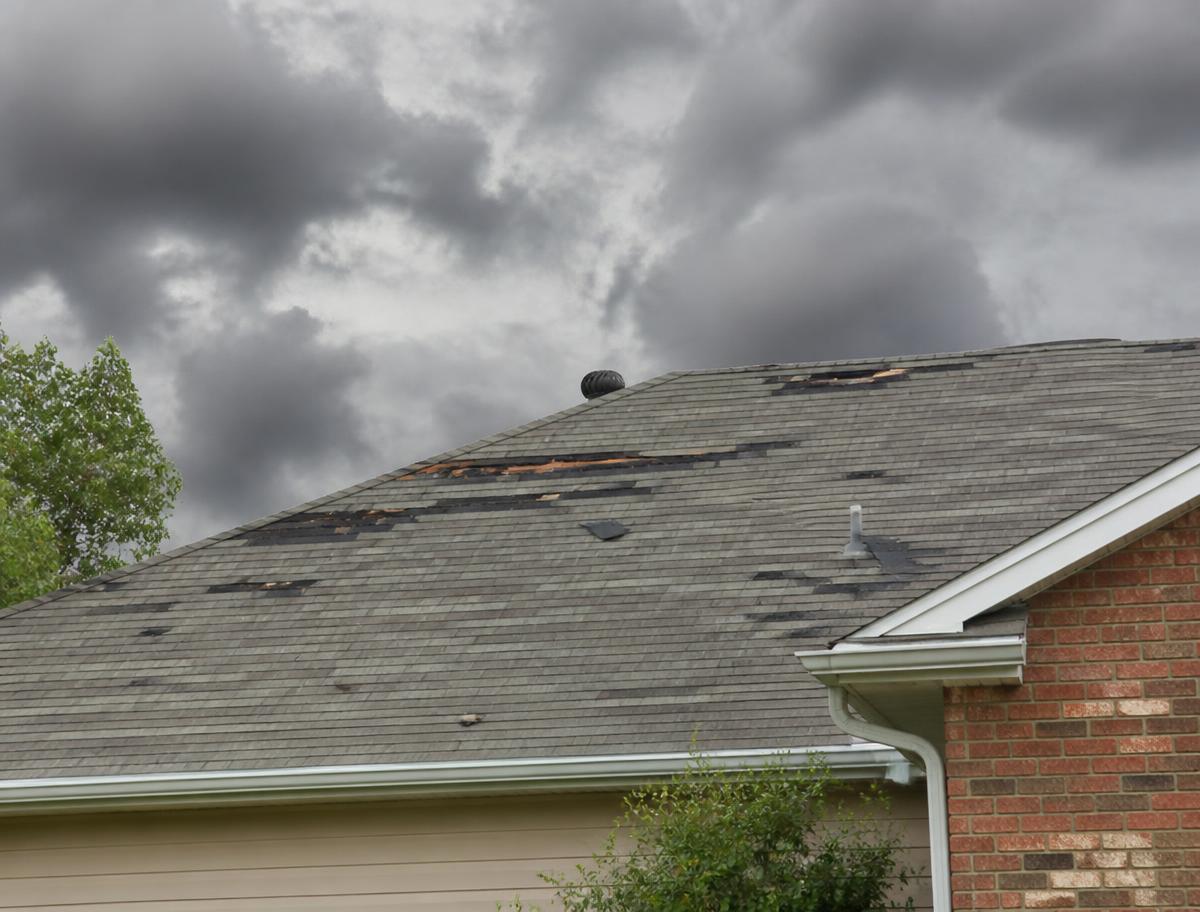 Storm damaged residential roof with missing shingles in Houston, TX